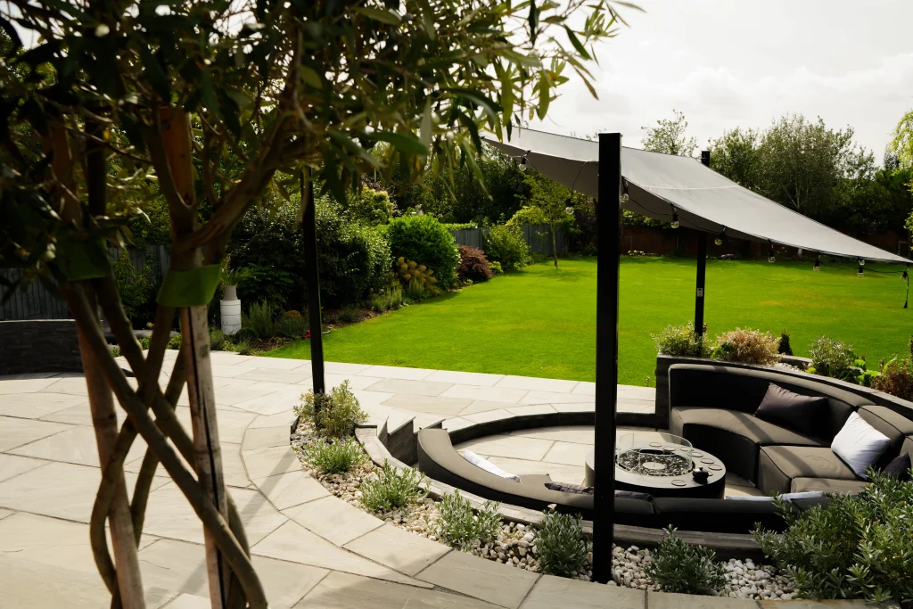 Relaxed garden seating area overlooking a wide lawn and layered planting in Massingham.